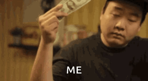 A Man Is Holding A Stack Of Money In His Hand And Says `` Me '' . GIF