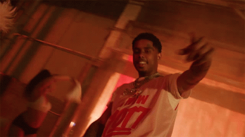 A Man Is Holding A Stack Of Money In His Hands And Wearing A White Shirt With The Number 7 On The Front GIF