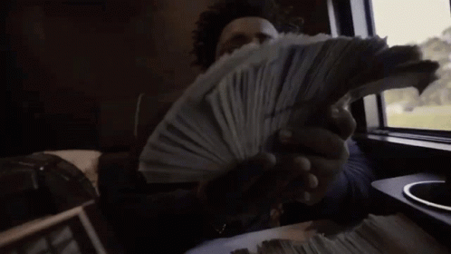A Man Is Holding A Stack Of Money In His Hands While Sitting In A Car . GIF