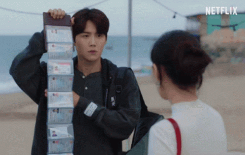 A Man Is Holding A Stack Of Passports In Front Of A Woman And The Word Netflix Is On The Bottom Right GIF