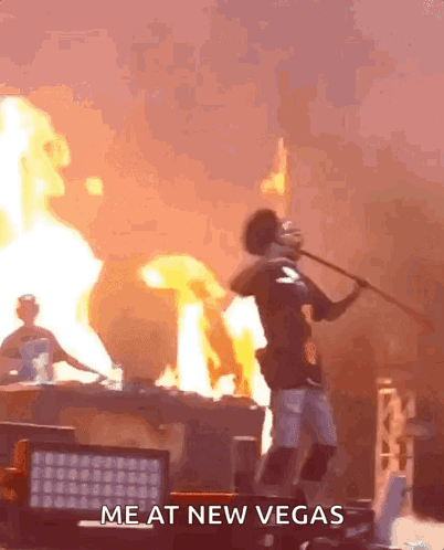 A Man Is Holding A Stick In Front Of A Fire With The Words Me At New Vegas Written On The Bottom GIF