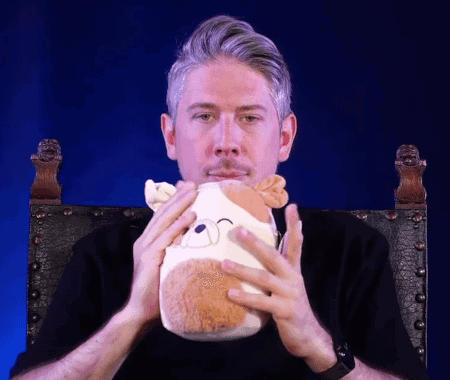 A Man Is Holding A Stuffed Animal In His Hands GIF
