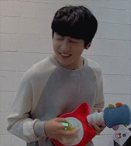 A Man Is Holding A Stuffed Animal In His Hands And Smiling GIF