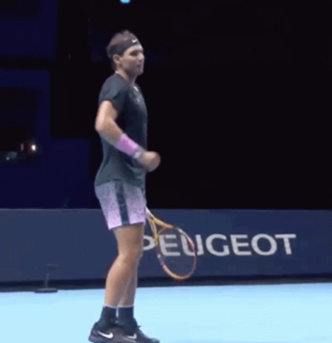 A Man Is Holding A Tennis Racket In Front Of A Peugeot Sign GIF