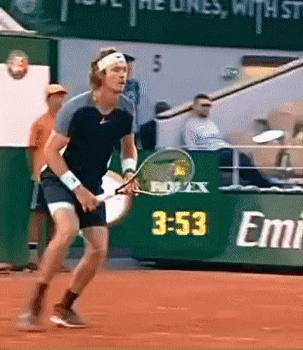 A Man Is Holding A Tennis Racket In Front Of A Sign That Says Emirates GIF