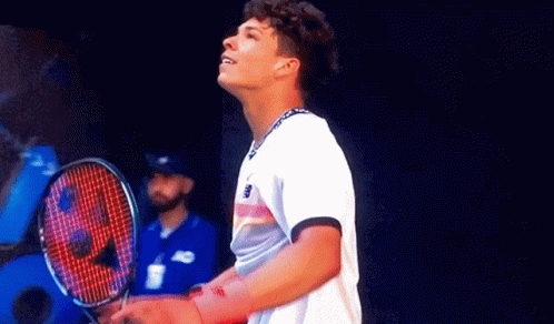 A Man Is Holding A Tennis Racquet And Looking Up GIF