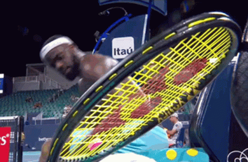 a man is holding a tennis racquet in front of an itau banner