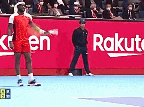 a man is holding a tennis racquet on a tennis court in front of a rakuten sign .