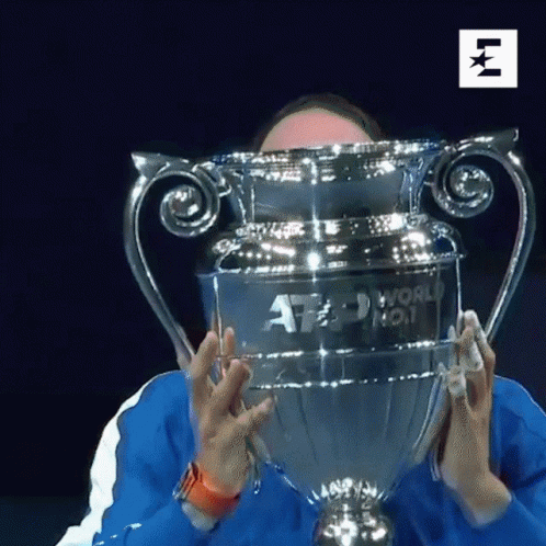 A Man Is Holding A Trophy In Front Of His Face That Says Atp World No. 1 GIF