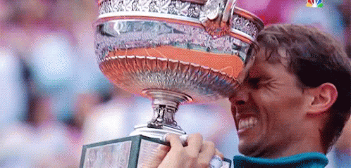 A Man Is Holding A Trophy In His Hand And Kissing It On His Forehead . GIF