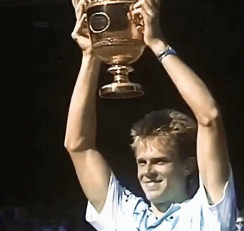A Man Is Holding A Trophy In His Hands GIF