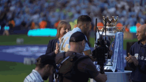 A Man Is Holding A Trophy That Says Premier League On It GIF