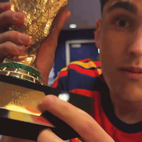 a man is holding a trophy that says ' world cup ' on it