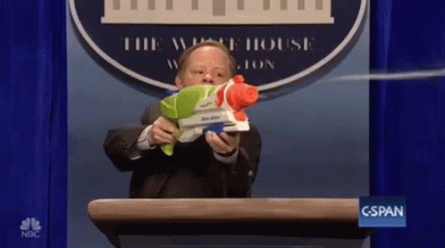 A Man Is Holding A Water Gun In Front Of A White House Logo GIF