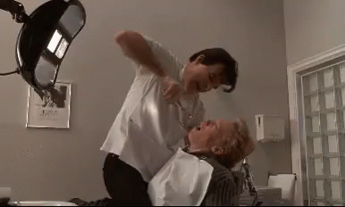 A Man Is Holding A Woman In A Dental Chair While A Dentist Cuts Her Teeth . GIF