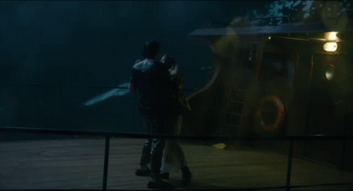 A Man Is Holding A Woman In A White Dress In The Rain GIF