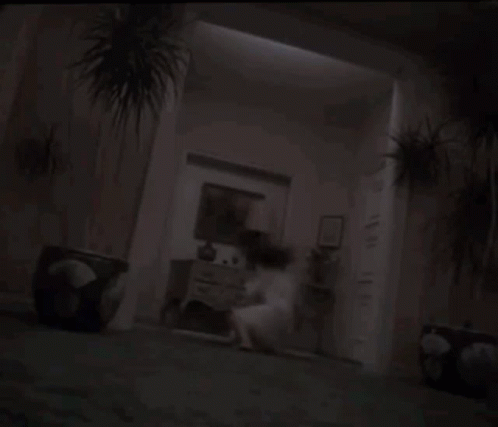 a man is holding a woman in his arms in a dark room in a horror movie .