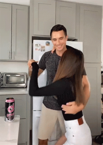 A Man Is Holding A Woman In His Arms In A Kitchen Next To A Can Of Gatorade .. GIF