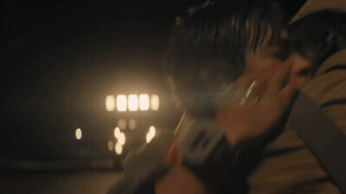 A Man Is Holding A Woman In His Arms In The Dark . GIF