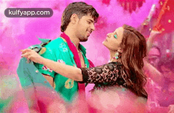 A Man Is Holding A Woman In His Arms While They Are Dancing In A Pink Room . GIF