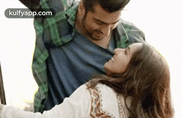 A Man Is Holding A Woman In His Arms While They Are Dancing Together . GIF