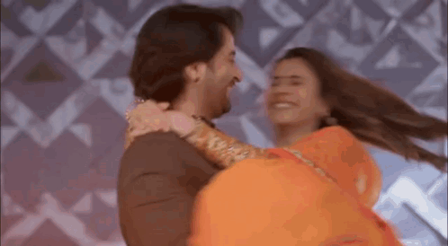 A Man Is Holding A Woman In His Arms While They Are Dancing Together . GIF