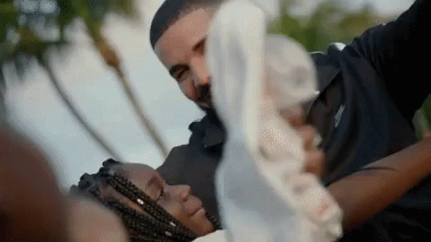 A Man Is Holding A Woman In His Arms While They Are Laying Down . GIF