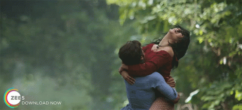 A Man Is Holding A Woman In His Arms With The Words Zee5 Download Now On The Bottom Right GIF