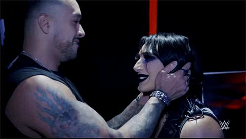 A Man Is Holding A Woman 'S Face With A W Logo In The Background GIF