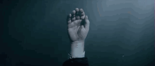 A Man Is Holding A Woman 'S Hand In A Dark Room . GIF
