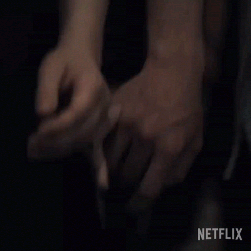 A Man Is Holding A Woman 'S Hand In A Dark Room . GIF