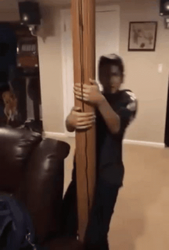 A Man Is Holding A Wooden Pole In A Living Room . GIF