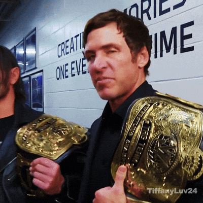 A Man Is Holding A Wrestling Belt In Front Of A Wall That Says " Create One Eve " GIF