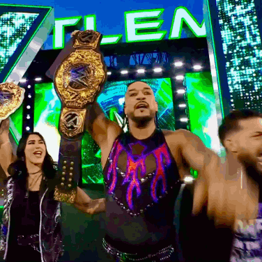 A Man Is Holding A Wrestling Championship Belt In Front Of A Sign That Says " T-Len " GIF