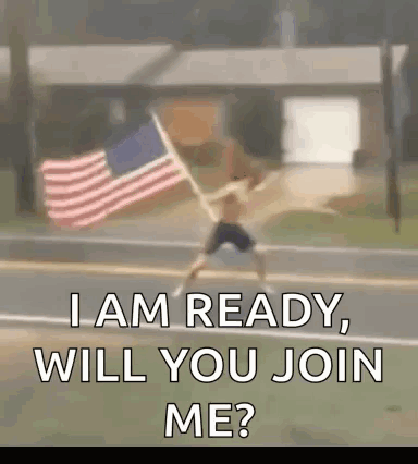 A Man Is Holding An American Flag On The Side Of A Road . GIF