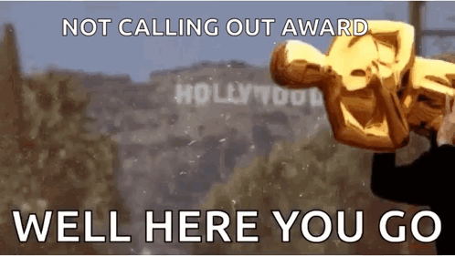 A Man Is Holding An Oscar Statue In Front Of Hollywood Sign GIF