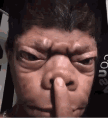 A Man Is Holding His Finger To His Nose . GIF