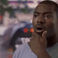 A Man Is Holding His Hand To His Chin And Looking At The Camera . GIF