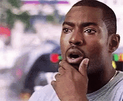 A Man Is Holding His Hand To His Chin And Looking Surprised . GIF