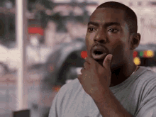 A Man Is Holding His Hand To His Chin And Making A Funny Face . GIF