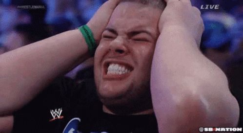 A Man Is Holding His Head In Pain While Watching A Wrestling Match On Sb Nation . GIF