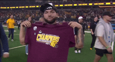 a man is holding up a shirt that says champions on it