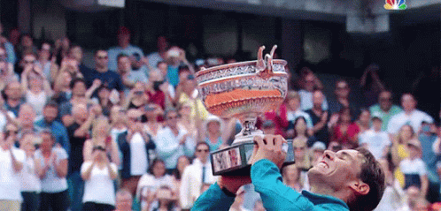 A Man Is Holding Up A Trophy In Front Of A Crowd Of People . GIF