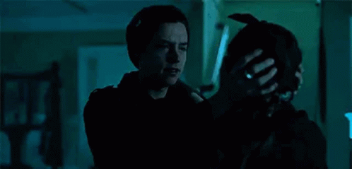 A Man Is Hugging A Woman In A Dark Room While Holding A Dog . GIF