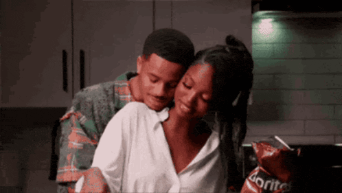 A Man Is Hugging A Woman In A Kitchen With Doritos Chips In The Background GIF