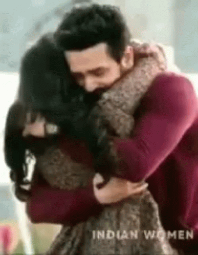 A Man Is Hugging A Woman In A Living Room . GIF
