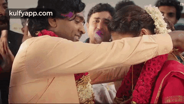 A Man Is Hugging A Woman In A Red Dress . GIF