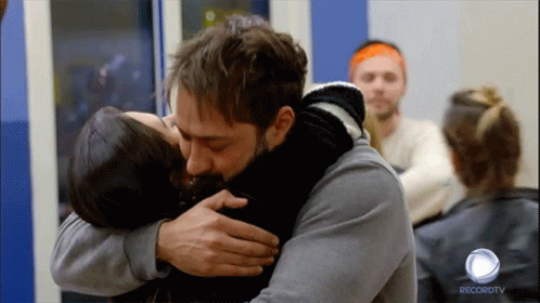 A Man Is Hugging A Woman In Front Of A Recordtv Logo GIF