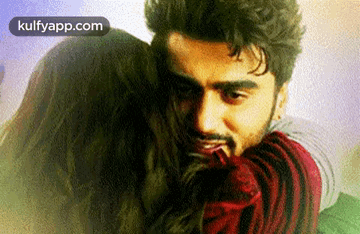 A Man Is Hugging A Woman With The Words Kulfyapp.com Written In The Corner . GIF