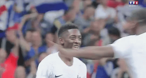 A Man Is Hugging Another Man On A Soccer Field While A Crowd Watches . GIF